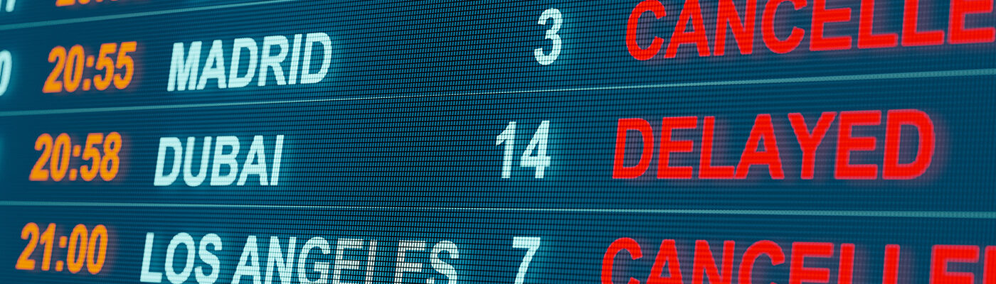 Close up of arrivals board showing flights from several destinations either cancelled or delayed